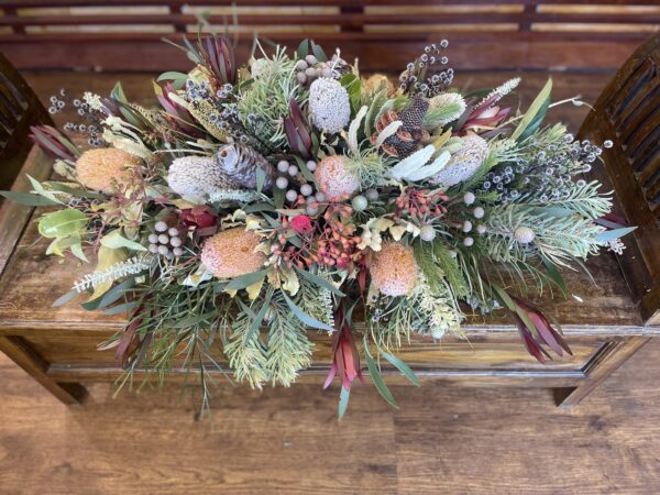 Elegant wildflower casket spray featuring a mix of Australian native blooms such as Protea, Banksia, and Eucalyptus, arranged in a respectful and serene design for a dignified tribute