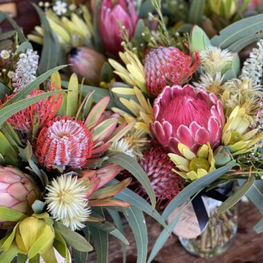 Charming wildflower posy jar showcasing native Australian flowers such as banksia,leucadendrons,soft gum leaves arranged in a simple glass jar for a fresh, natural look