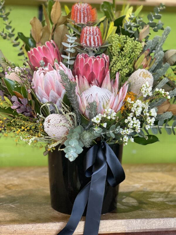 Elegant corporate wildflower arrangement featuring Australian native blooms such as Protea, Banksia, and other wildflowers in a modern vase, designed to enhance office spaces with natural beauty